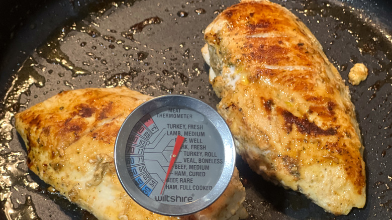 Cuisson du poulet dans une poêle avec un thermomètre à viande pour vérifier la température