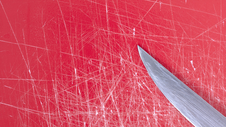 Surface fortement rayée d'une planche à découper en plastique rouge