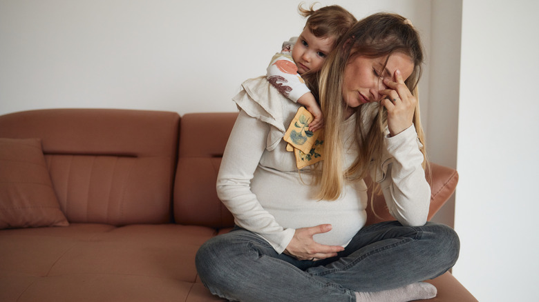 Femme enceinte éprouvant un inconfort pendant qu'un jeune enfant la serre dans ses bras