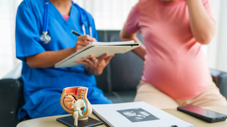 Médecin tenant un presse-papiers tout en parlant avec une personne enceinte