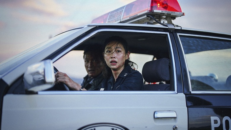 Hoyeon dans le rôle de Sung-ae conduisant une voiture de police à côté de Hwang Jung-min dans le rôle de Bum-seok dans Hope