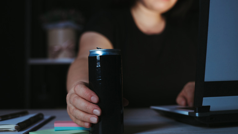 Une femme qui cherche une boisson énergisante peut tout en travaillant la nuit
