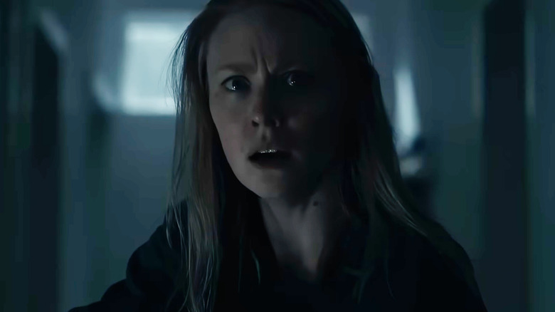 Deborah Ann Woll dans le rôle de Meg, l'air alarmée dans un couloir sombre dans The Cycle