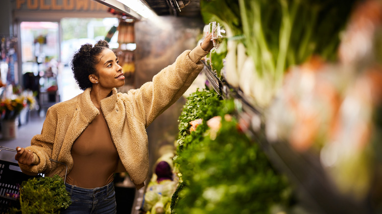 Femme parcourant l’allée des légumes du magasin