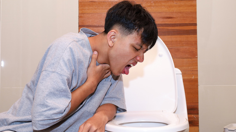 Homme essayant de vomir dans la cuvette des toilettes