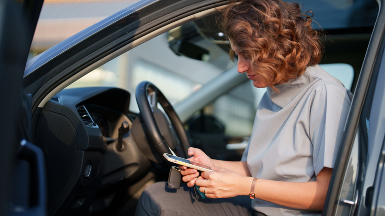 Une femme utilisant son smartphone sur le siège d’une voiture.