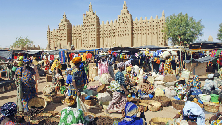 Une scène de marché colorée au Mali avec des gens, des paniers et des kiosques.