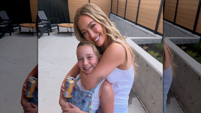 Hilary Duff porte ses cheveux blonds en vagues de sirène tout en portant un débardeur blanc et en posant avec sa fille Banks pendant sa 