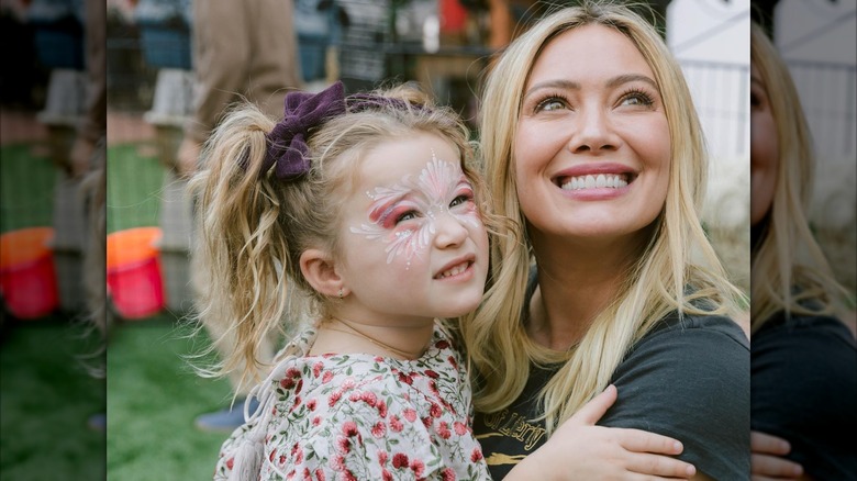 Hilary Duff porte ses cheveux blonds raides tout en souriant et en tenant sa fille Banks lors de sa troisième fête d'anniversaire.