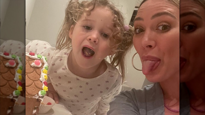 Hilary Duff et sa fille Banks tirent la langue tout en décorant une maison en pain d'épice en pyjama.