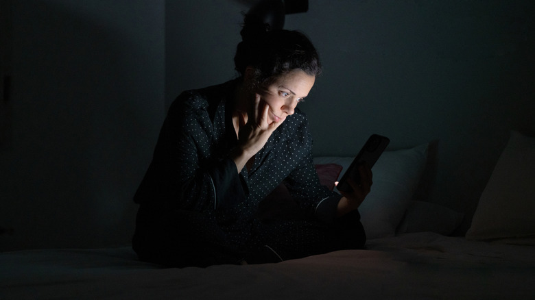 Femme au lit qui semble faire défiler la catastrophe la nuit.
