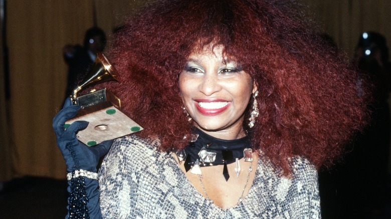 Chaka Khan est photographiée avec son afro rouge emblématique tout en souriant et en tenant un Grammy Award