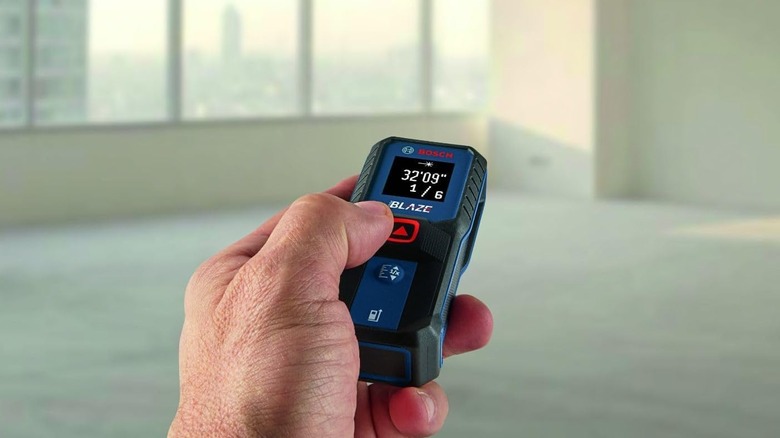 homme utilisant une mesure laser