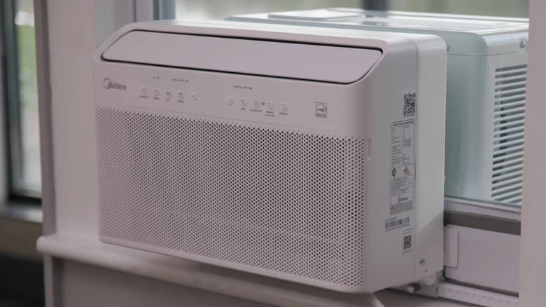 Gros plan du climatiseur de fenêtre Midea en forme de U sur une fenêtre, pompe à chaleur cachée en arrière-plan
