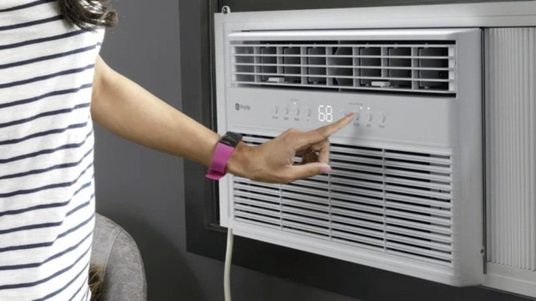 Une femme ajustant les commandes avant d’un climatiseur de fenêtre GE Profile.