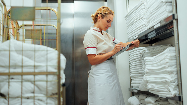 femme dans la buanderie de l'hôtel avec des serviettes