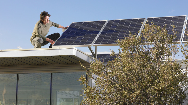 Homme inspectant des panneaux solaires résidentiels installés sur des supports