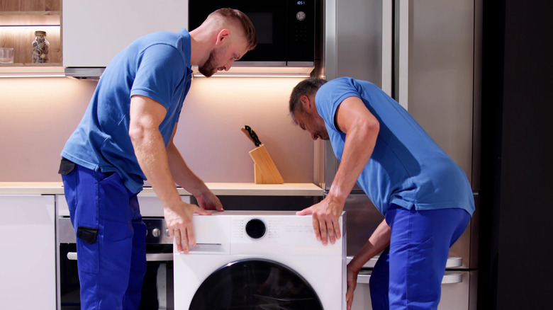 Deux hommes déplaçant une laveuse en place