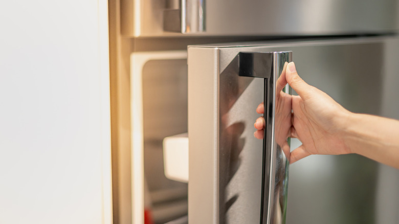 Gros plan d'une main ouvrant la porte d'un réfrigérateur