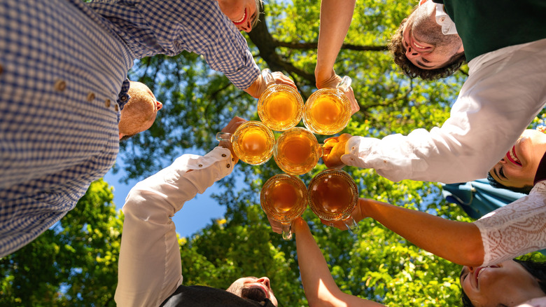 Photo ci-dessous d'un groupe d'amis trinquant sous les arbres dans un café en plein air allemand