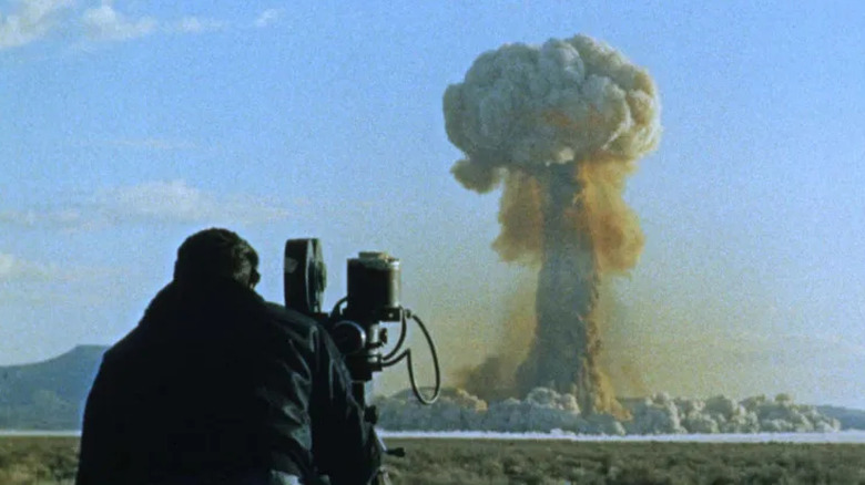 Un caméraman filme l'explosion d'une bombe atomique à distance, un grand champignon atomique