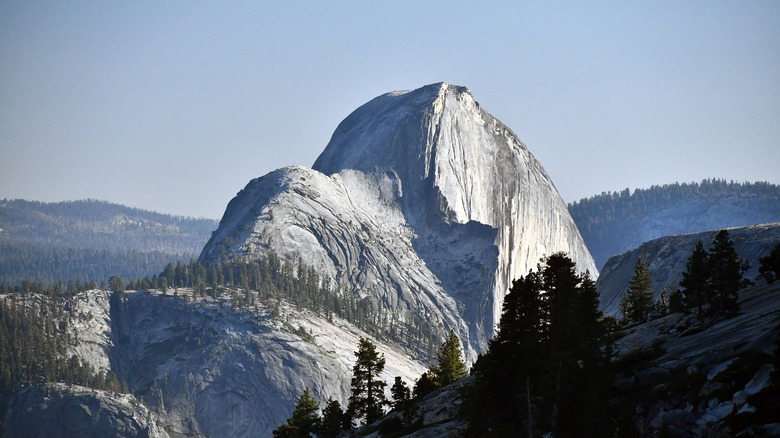 vue depuis Olmstead Point du Half Dome s'avançant dans le ciel, avec la forêt et les montagnes environnantes