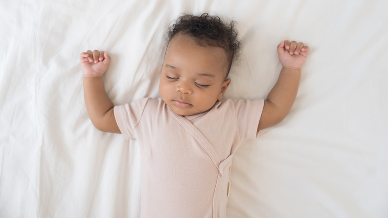 Bébé dort les bras levés