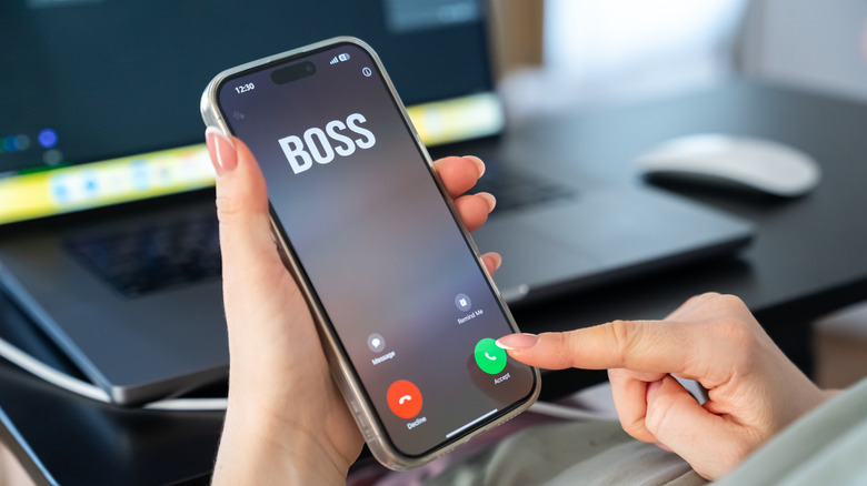 Une personne tient un smartphone qui affiche un appel entrant de son patron