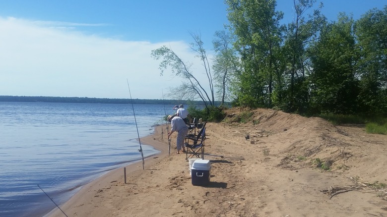 pêcheurs sur la plage de sable du lac Petenwell avec cannes à pêche et fournitures