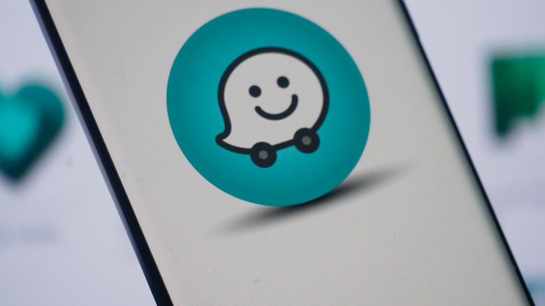logo waze sur l'écran d'un smartphone placé sur un fond clair