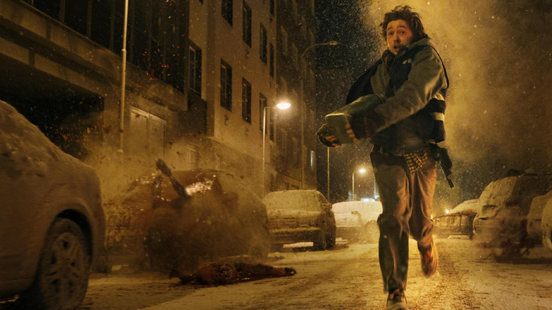 Austin Abrams dans le rôle de Bryan courant dans la rue alors que des corps explosent autour de lui dans Resident Evil (2026)