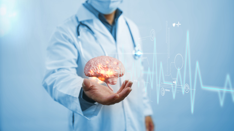 Médecin de sexe masculin tendant la main avec un cerveau CGI flottant dans sa paume