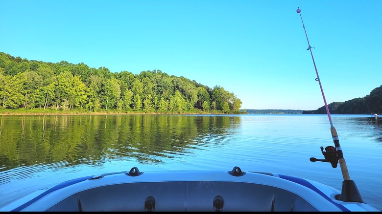Un bateau avec une canne à pêche donnant sur un lac calme et une forêt.