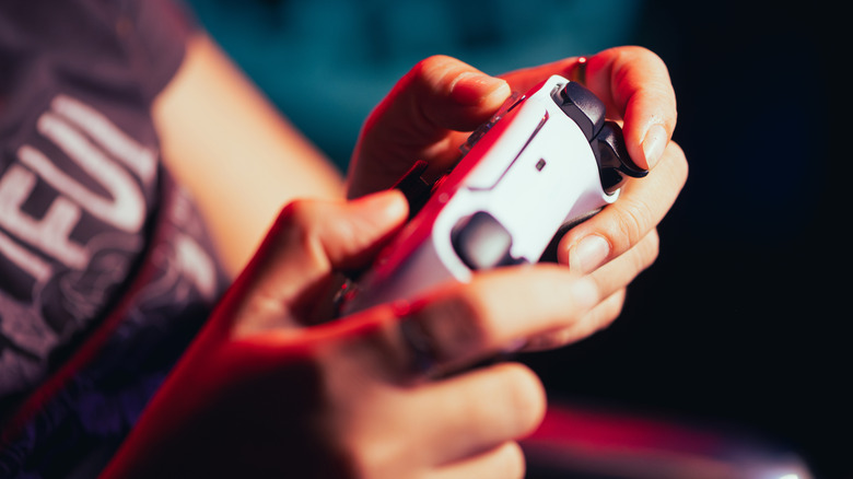Une personne tenant une manette PlayStation 5
