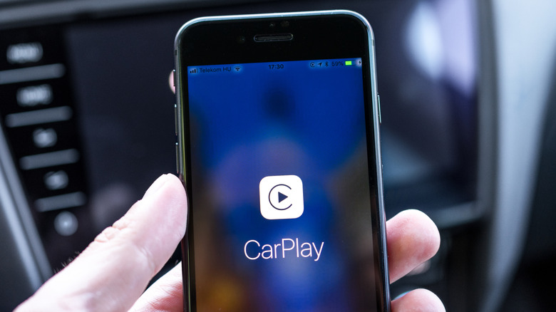 Une personne tenant un iPhone avec CarPlay affiché dessus