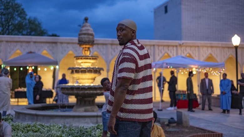 Mahershala Ali dans le rôle de Latif portant une casquette de prière taqiyah et debout dans la cour d'une mosquée dans Your Mother Your Mother Your Mother