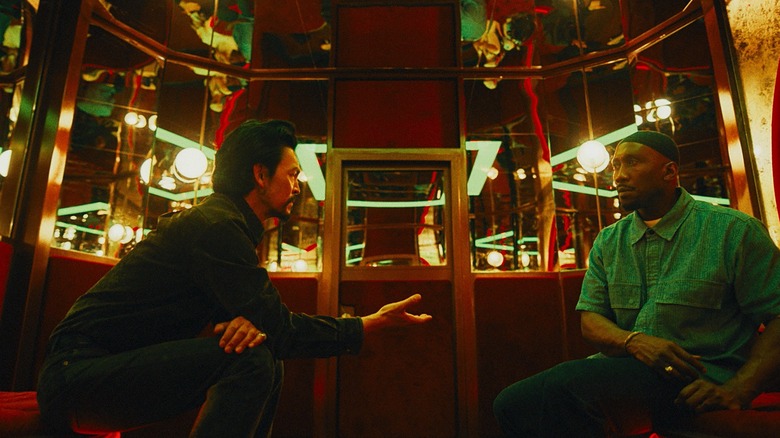 John Cho dans le rôle de Hwan Yoon tendant la main à Mahershala Ali dans le rôle de Latif dans une salle privée pleine de miroirs dans Your Mother Your Mother Your Mother