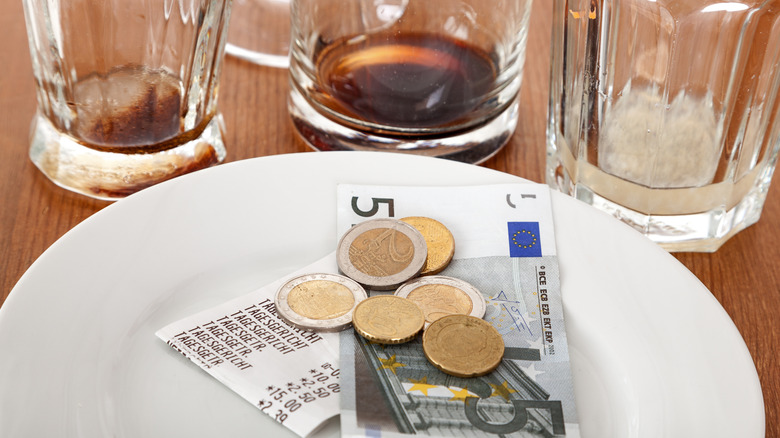Quelques pièces de monnaie et euros en papier avec un reçu sur une assiette
