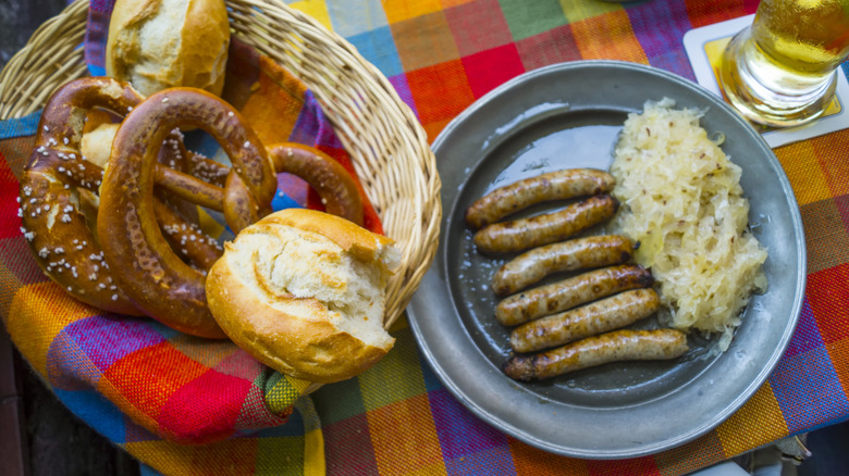 Un panier de bretzels et de petits pains à côté d'une assiette de saucisses et de choucroute
