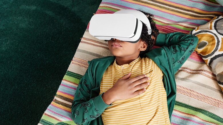 Jeune garçon posé sur un matelas à motifs avec un casque VR dessus