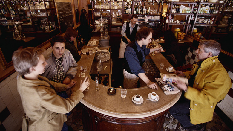 Des gens debout autour d’un comptoir buvant du café en France
