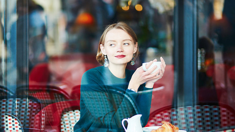 Une jeune femme buvant du café assise dans un café à Paris