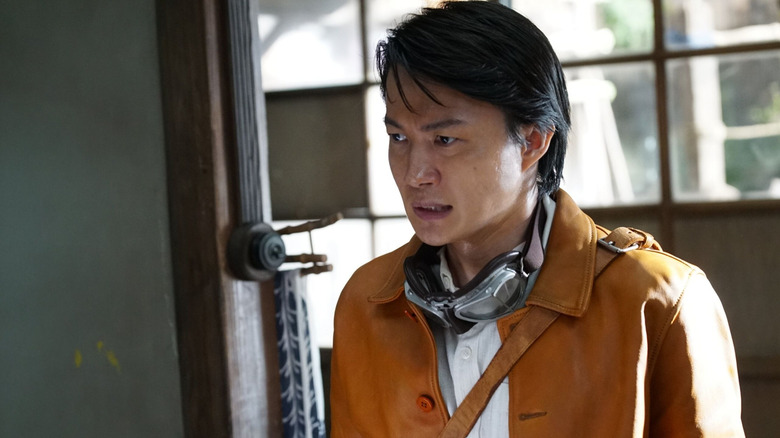 Ryûnosuke Kamiki dans le rôle de Kôichi Shikishima debout près d'une porte avec des lunettes autour du cou dans Godzilla Minus Zero