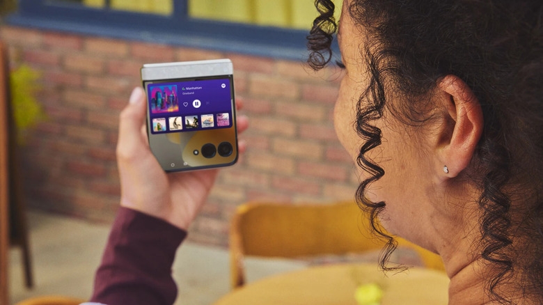 Une personne tenant un Motorola Razr 2026 plié avec de la musique dessus