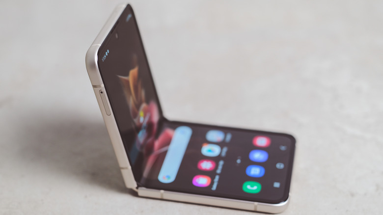 Un smartphone à clapet, posé à moitié plié sur une surface blanc cassé