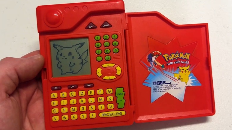 Une main tenant le Pokédex Pokémon Tiger Electronics s'est ouverte avec Pikachu sur l'écran