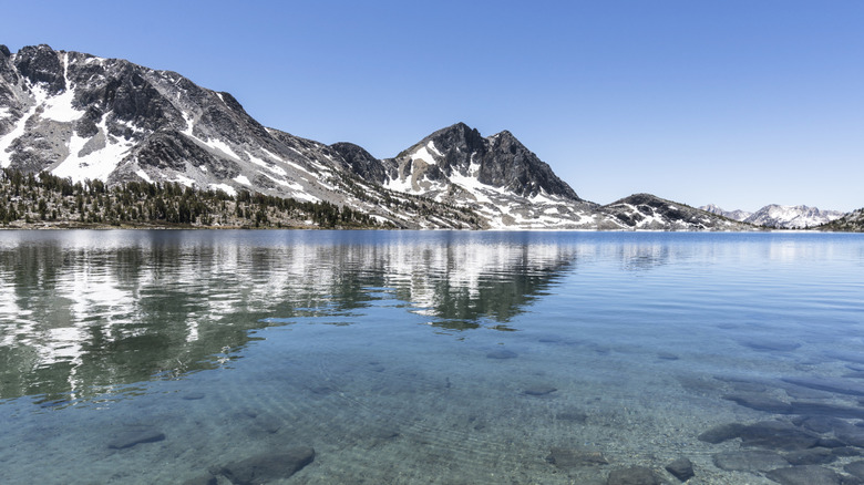 Un lac clair en hiver avec des montagnes semi-enneigées autour