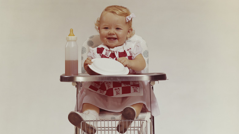 Petite fille assise dans une chaise haute à l'ancienne