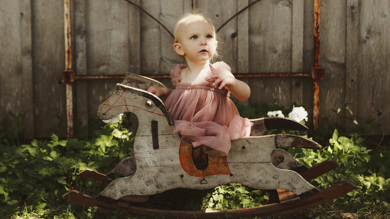 Une petite fille sur un cheval à bascule vintage