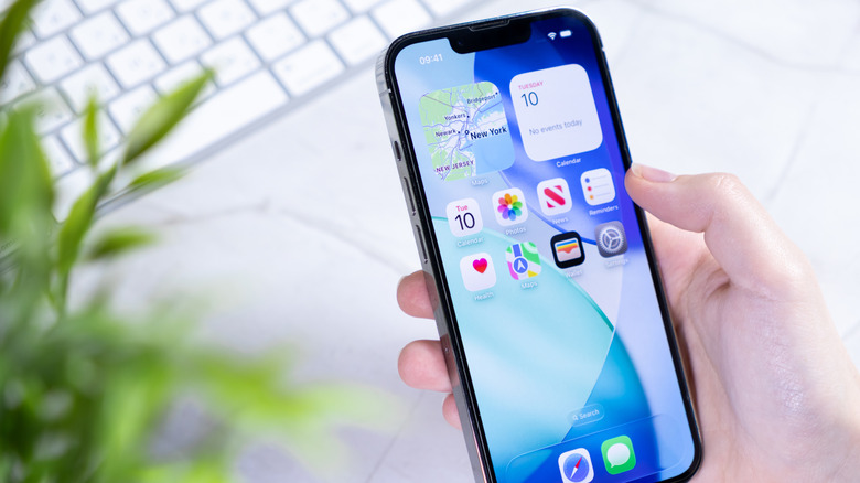 Une personne tenant un iPhone avec un focus sur l'écran d'accueil